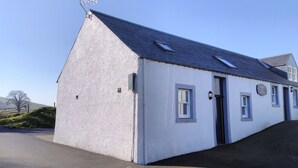 Un bâtiment blanc avec un toit en pente, une petite fenêtre et une porte.