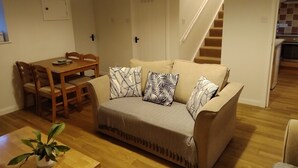 Un salon confortable avec un canapé, une table à manger et des chaises. Un escalier mène à un autre niveau.