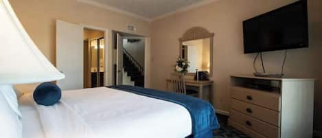 A hotel room with a bed, a desk, a dresser, a TV, and a staircase leading to another room.