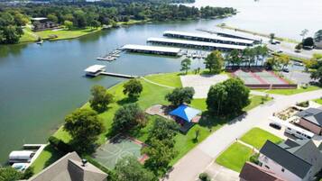 An aerial view of a lakeside property with a marina, tennis courts, and residential buildings.