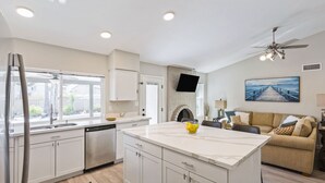 Een moderne keuken met witte kasten, een centraal eiland en een zithoek met een bank.