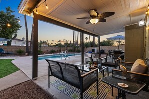 Une terrasse extérieure avec une piscine, des sièges et un ventilateur de plafond.