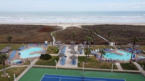 Relax by the resort's central pool, surrounded by smaller pools and lounge areas, with access to the beach and a tennis court.