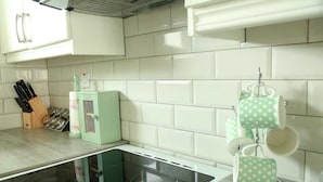 A kitchen with white tiles, a stove, a green egg carton, and a knife block. - Killarney Town Center (Killarney)