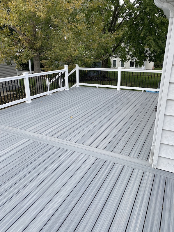 A wooden deck with white railings and a view of a house in the background. - Just Peachy Peninsula Cottage -- Outside of Lakeside (LKSID MARBLHD)