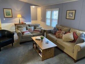 A living room with two sofas, a coffee table, a lamp, and framed pictures on the walls. - Just Peachy Peninsula Cottage -- Outside of Lakeside (LKSID MARBLHD)