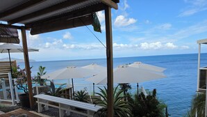 A terrace with outdoor seating, umbrellas, and a view of the sea. - Balisier Suite, sea and pool view. (Schoelcher)