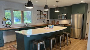A modern kitchen with a large island, stainless steel appliances, and bar stools. - Perfect lake home for a family get away - Only 1 hour from metro (South Haven)