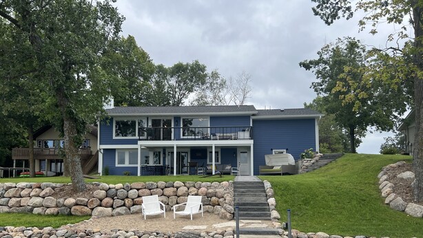 A two-story house with a deck and a stone wall. - Perfect lake home for a family get away - Only 1 hour from metro (South Haven)