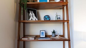 A wooden bookshelf with various items including books, a clock, and decorative objects. - The Lookout - Stylish penthouse with sea views (Ramsgate)