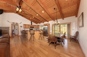 Una cocina amplia con armarios de madera, una isla central y un comedor con sillas de madera.