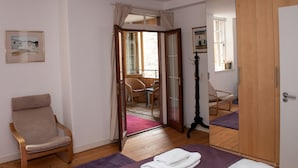 Ein Hotelzimmer mit Bett, Stuhl, Holzboden, Tür und Fenster.