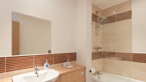 Ein modernes Badezimmer mit einem großen Waschbecken, einem Spiegel und einer Dusche.
