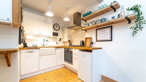 Una cucina moderna con mobili bianchi, piani in legno, forno integrato e decorazione murale a tema caffè.