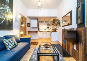 Ein modernes Wohnzimmer mit einer Couch, einem Glastisch und einer Küche im Hintergrund.