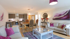 A modern living room with a sofa, a coffee table, and a dining area with chairs and a table. - A spacious open plan apartment, in an unbeatable city-centre location. Sleeps 4. (Edinburgh)