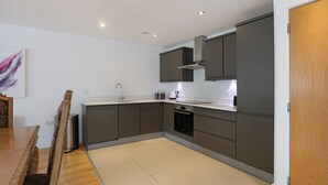 A modern kitchen with grey cabinets, a stainless steel sink, and a built-in oven. - A spacious open plan apartment, in an unbeatable city-centre location. Sleeps 4. (Edinburgh)