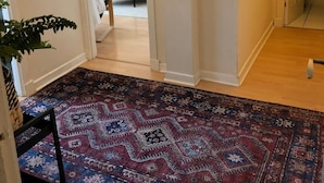A hallway with a patterned rug, a television in the background, and a door leading to another room. - Lovely one-bedroom apartment just a few yards off Edinburgh’s famous Royal Mile. Sleeps 2. (Edinburgh)