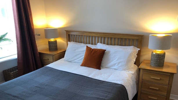 A neatly made bed with a blue blanket, two bedside lamps, and a wooden headboard. - Lovely one-bedroom apartment just a few yards off Edinburgh’s famous Royal Mile. Sleeps 2. (Edinburgh)