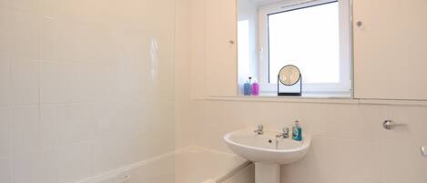 A bathroom with a bathtub, sink, mirror, and toilet.