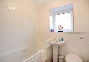 Ein Badezimmer mit Badewanne, Waschbecken, Spiegel und Toilette.