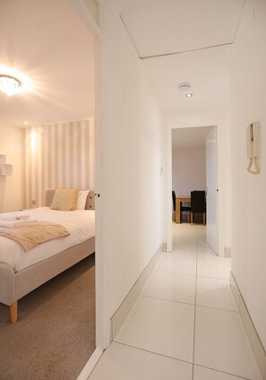 Une chambre d’hôtel comprenant un lit, une table de chevet, une chaise, une petite table avec des chaises et un téléphone.