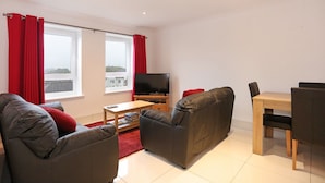 A modern living room with a sofa, TV, and dining table.