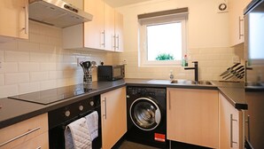 A compact kitchen with a built-in washer and dryer, a microwave, and a window providing natural light.