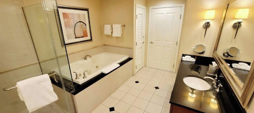 Een moderne badkamer met een douchecabine van glas, een ruim bad, een wastafel met spiegel en een toilet.