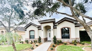 A two-story house with a front entrance, a covered porch, and a landscaped front yard with small shrubs and a palm tree. - Luxury Home❤️Las Villitas❤️Close to the Mall and Airport ❤️ (McAllen)