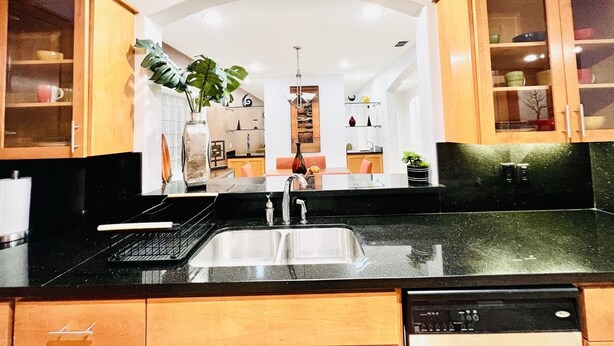 A modern kitchen with a black countertop, wooden cabinets, and a built-in dishwasher. - Luxury Home❤️Las Villitas❤️Close to the Mall and Airport ❤️ (McAllen)