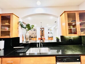 A modern kitchen with a black countertop, wooden cabinets, and a built-in dishwasher. - Luxury Home❤️Las Villitas❤️Close to the Mall and Airport ❤️ (McAllen)