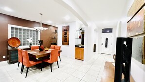 A modern dining area with a large table, orange chairs, and a chandelier. - Luxury Home❤️Las Villitas❤️Close to the Mall and Airport ❤️ (McAllen)
