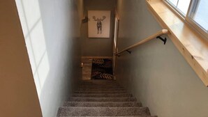 Eine schmale Treppe mit hölzernem Geländer und einem Fenster auf der rechten Seite.