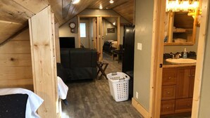 Ein gemütliches Schlafzimmer im Dachgeschoss mit Holzbalkendecke, einem Bett, einem kleinen Tisch und einem Wäschekorb.