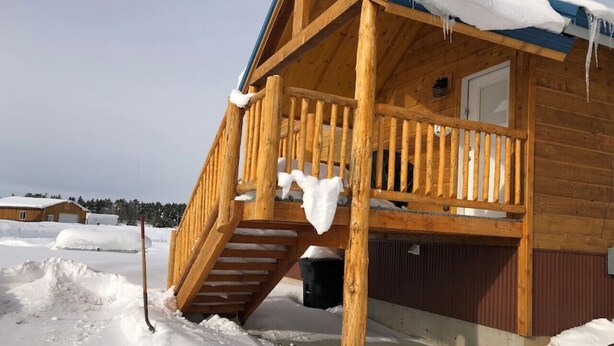 Eine Holzhütte mit einer Veranda und einer Treppe zum Eingang.