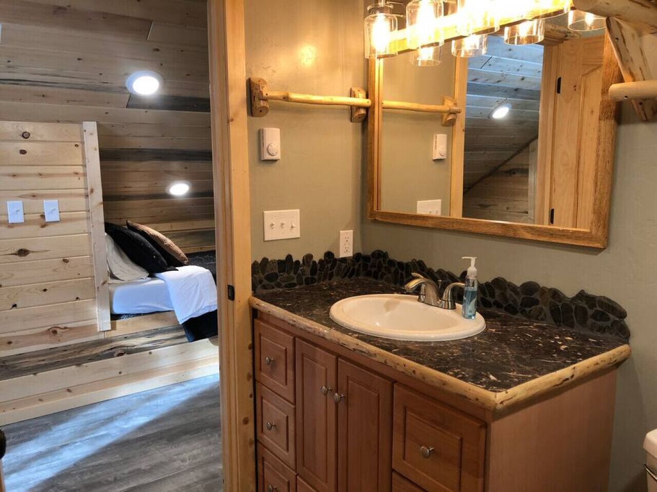 Ein Badezimmer mit einem Holzbadschränken, einem Waschbecken und einem Spiegel.