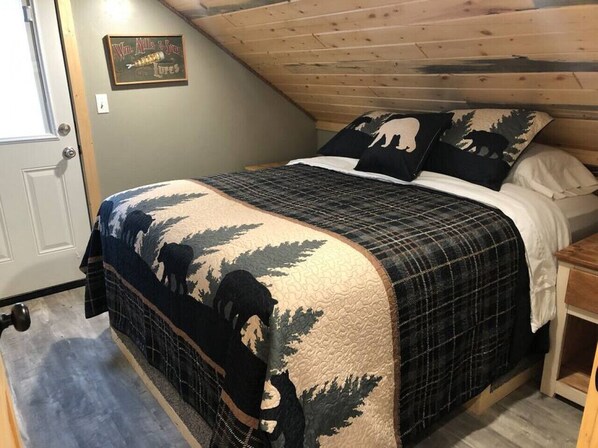 Une chambre à coucher avec un lit, une tête de lit en bois, une porte et une petite table.