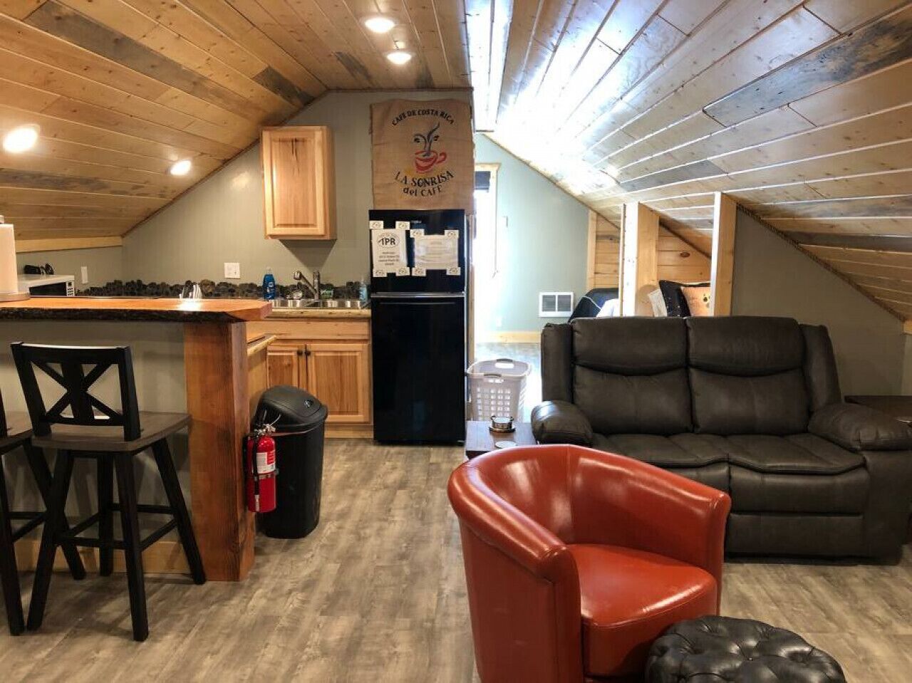 Un acogedor espacio tipo loft con cocina, comedor y zona de estar con sofá de cuero y una silla roja.