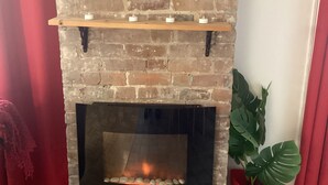 Una chimenea de ladrillo con tres repisas, un florero rojo y una planta en maceta.
