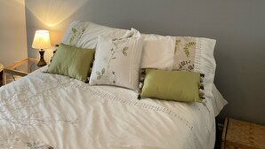 Un dormitorio con cama, almohadas, una mesita de noche y adornos en la pared, incluyendo estrellas y una luna creciente.
