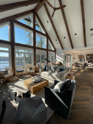 A spacious living room with large windows, wooden beams, and a view of the outdoors. - Incredible Cottage on Crystal Lake. Very private on 7 acres (Kinmount)
