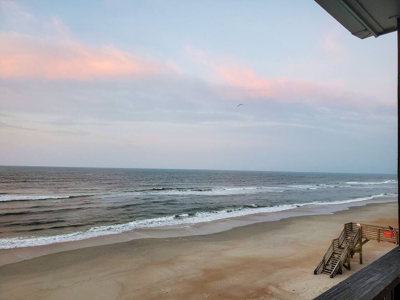 A beach view with a wooden deck and a flag.