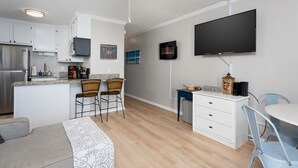 A modern kitchen with white cabinets, a built-in microwave, and a large island with bar stools. - The Lookout: Tranquil Beachfront Condo (North Topsail Beach)
