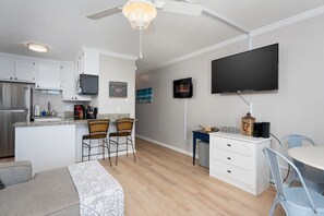 A modern kitchen with white cabinets, a built-in microwave, and a large island with bar stools. - The Lookout: Tranquil Beachfront Condo (North Topsail Beach)
