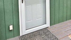 A white door with a glass panel and a metal handle, set in a green wooden wall with a number '2' above it.