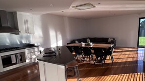 Una cocina moderna con una isla central, suelo de madera y un comedor con mesa y sillas.