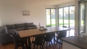 Una sala de estar moderna con una mesa de comedor de madera, sillas negras, un sofá gris y un cuadro en la pared.