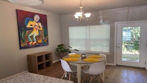 Un comedor con una mesa, sillas y un cuadro en la pared.