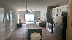 Una cocina moderna con una isla central, electrodomésticos integrados y una zona de comedor con sofá y sillas.